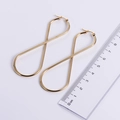 Pendientes de aro dorados con forma de infinito mostrados con regla para medidas - 【Dorado】19*45mm