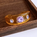 Macro-opname van barnsteenkleurige hars armband met paarse edelsteen en kristalaccenten - Gele Armband Met Paarse Steen