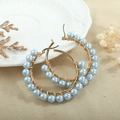 Detail of handmade gold hoop earrings with light blue pearls on woven texture fabric - Light Blue