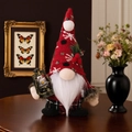 Détail d'un gnome de Noël avec bonnet à flocons et lanterne LED sur décor en bois - Gnome rouge avec lampe à huile homme