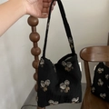 Detail of black jacquard shoulder bag with beige rose pattern and simple woven label - Small Handbag