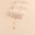Y-shaped gold necklace with staggered pink freshwater pearls on a white display - Gold Pearl Style