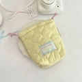 Quilted yellow camera storage bag with pink drawstrings on a decorative white plate - Gourd Pattern Soft Yellow
