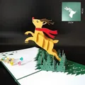 Carte de Noël 3D avec un renne jaune sautant au-dessus d'une forêt de papier découpé - Cerf de la Forêt / 15x15cm
