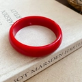 Macro shot of a vibrant red resin bangle with a polished finish placed on an art book - Red