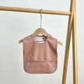 Detail of baby waterproof bib in dusty rose with large food catcher on wooden hanger - Fashion Pink