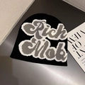 Close-up of black knit beanie featuring gray and white Rich Mob street style lettering - Black + White Letters