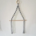 Détail d'un porte-papier mural en macramé gris avec tige en bois et franges en coton - 45*30cm / Gris