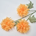 Close-up of three orange silk pompon chrysanthemum artificial flowers with green leaves - Orange