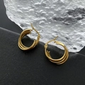 Minimalistische drielaagse gouden oorringen op een zwart gestructureerd oppervlak - Drielaagse in elkaar gevlochten ring / Goud
