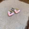 Detailopname van roze hartvormige oorbellen op getextureerd beige papier - Roze hart oorbel