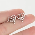 Macro detail of silver stainless steel heart-shaped music note stud earrings on fingers - Steel