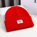 Close-up of red knit beanie featuring a white woven patch with black English text - 56-58cm / Red