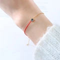Red cord and gold chain bracelet featuring a round gradient blue gemstone charm - December Blue Zircon