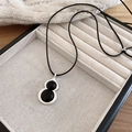 Gros plan du pendentif gourde en argent avec onyx noir sur fond en maille de haute qualité - Forme de Gourde