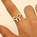 Close-up of an 18K gold stainless steel ring with a white enamel bow on a finger - White Enamel Bow Style (WG-0482)