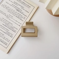 Close-up of a matte khaki rectangular hair claw clip on an open English book page - Matte Khaki