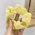 Close-up of yellow ruffled scrunchie made of textured fabric held against a window - 3# Yellow