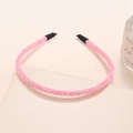 Detailed view of pink glitter headband with protective black tips on smooth surface - Pink