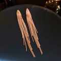Macro-opname van rosƩgouden lange kwastjes oorbellen met elegante V-vormige metalen ketting - Zilveren Pin - Gouden Ketting Kwastje Oorbellen / Goud