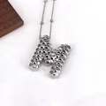 Minimalist silver necklace with M initial pendant featuring textured surface and thin chain - M