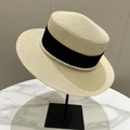Detalle de elegante sombrero de paja con incrustaciones de perlas y cinta negra en soporte - Beige