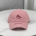 Pink distressed baseball cap with M embroidery on a marble surface in a top-down view - Pink