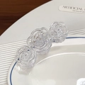 Drei klare Acryl-Haarklammern in Kamelienblüten-Optik auf einem weißen Keramikteller - 11cm / Transparent