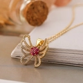Collana con ciondolo a farfalla dorata con zirconi chiari e pietre rosse su un libro - Rosso