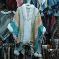 Detail of knitted poncho featuring faux fur collar and colorful zigzag pattern with tassels - White Green