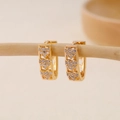 Nahaufnahme goldener V-Ohrringe mit drei mit Zirkonia besetzten Herzen auf einem Holzständer - EH410023-Gold Vertikale Drei Herzen