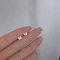 Elegant gold butterfly stud earrings showing delicate size on a fingertip display - Folded Butterfly / Gold