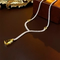 Dettaglio collana dorata con gemma gialla a goccia e cristalli pavé su sfondo in pelle - Collana / Giallo