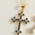 Macro del ciondolo a croce dorata con zirconi blu e bianchi incastonati a mano - Zirconia Blu Reale