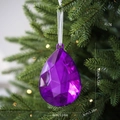 Lila Weihnachtsschmuck in Tropfenform mit weißem Band an einem Tannenbaumzweig - Wassertropfen Edelstein / Lila