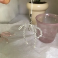 Dettaglio macro del ciondolo per telefono in cristallo fatto a mano con perle e stella - Fiocco di Cristallo Bianco / Bianco