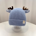 Close-up of light blue knitted baby hat with reindeer antlers and Baby label decoration - Hat - Blue