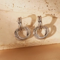 Detail view of interlocking silver stainless steel hoop earrings on champagne silk fabric - Five-Ring Interlocking Style