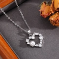Dettaglio della collana con cuore in argento con cristalli lucidi e perla bianca - Stile Cuore Traforato con Perla Argento (T026)