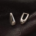 Minimalist silver teardrop huggie earrings with a polished mirror finish on black silk - Small Silver Teardrop Ear Buckle