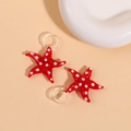 Detail shot of a red 3D glass starfish pendant with white polka dots and a clear loop - Red