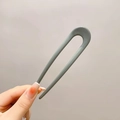 Minimalist grey U-shaped hair fork accessory held in hand for bun styling - ABS / Bean Green