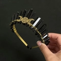 Detail of gold crystal headband with black spikes and central moon motif held by hand - Black + Gold Wire Gold Headband Gold Moon