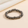 Dettaglio di anello elastico con perline metalliche grigio scuro e finitura in ematite - Grigio Scuro Metallizzato