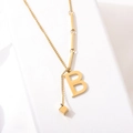 Collier en acier titane doré avec pendentif lettre B et pompon sur fond blanc - Or Lettre B (8847)
