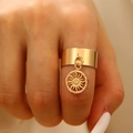 Detailed close-up of a wide gold ring featuring a round sun totem pendant on a finger - Sun Style (N-1066)