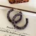Détail de boucles d'oreilles rondes vintage imprimé léopard sur un livre rétro élégant - Léopard Gris