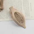 Matte beige oval hair claw clip with internal teeth placed on an open book page - Matte Skin