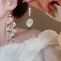 Dettaglio di orecchini di perle con lunghe nappe bianche indossati da una modella donna - Ganci per orecchini / Bianco