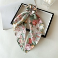 Detail of satin floral print scrunchie with long ribbons on a decorative tray - Green Big Floral